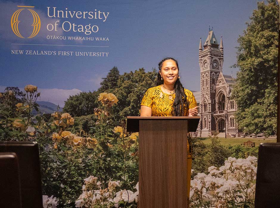 a woman stands behind a lecturn while addressing an audience