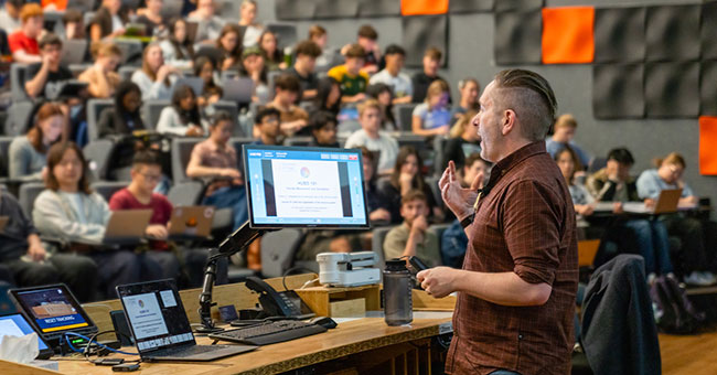 Lecturer at lectern in front of student audience