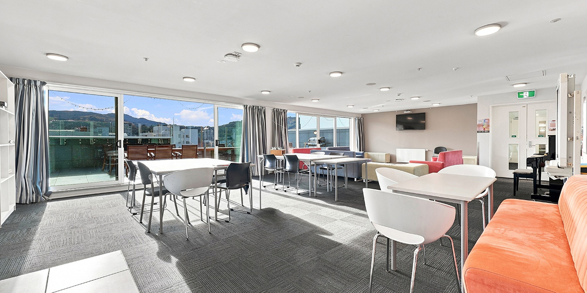 Shared common room with tables, sofas and access to an outdoor deck area
