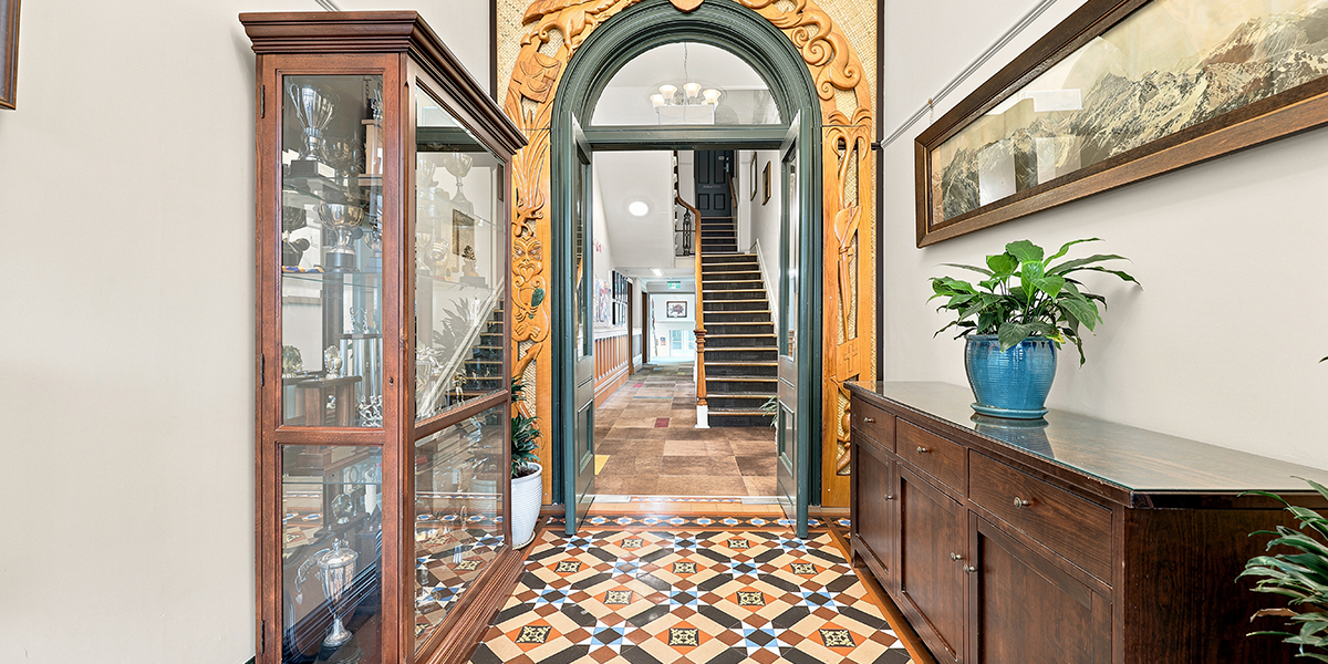 Entrance hall featuring a carved wooden archway, trophy cabinet, tiled floor, and staircase.