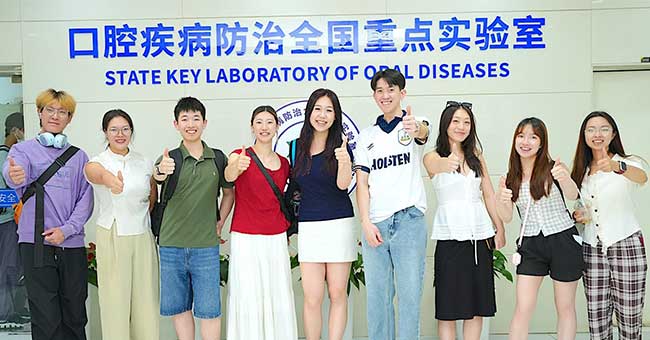 a row of students stand in front of a wall with Chinese scripture on it and State Key Laboratory of oral diseases under the scripture