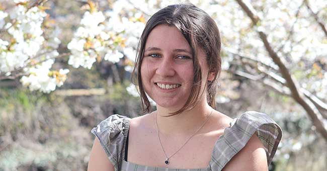 head and shoulders of a woman with blossom trees in the background