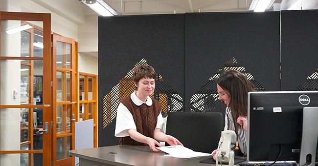 Two people interacting at a library service desk