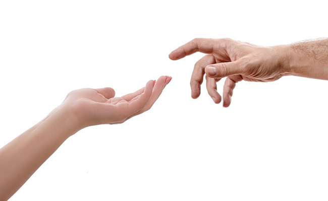 Stock photograph of two people's hands reaching towards each other against a white background