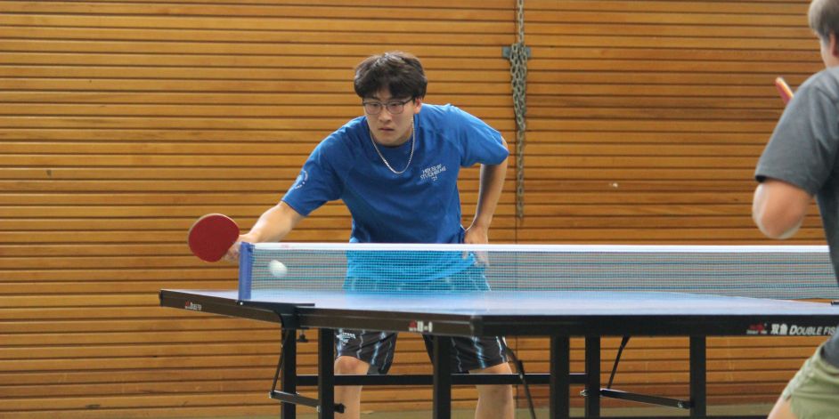 Two students playing a game of table tennis.