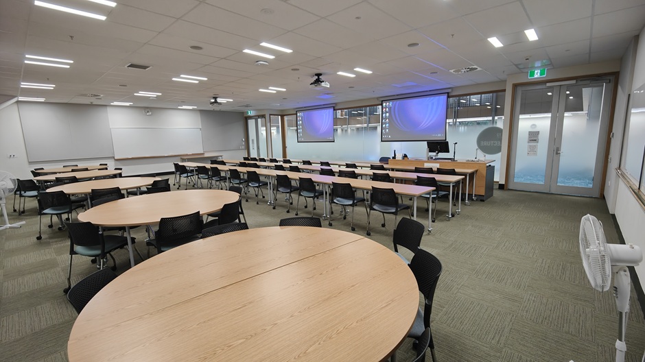 View of Otago Business School room 119, showing tables and chairs in rows and groups