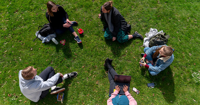 students sitting on campus lawn 