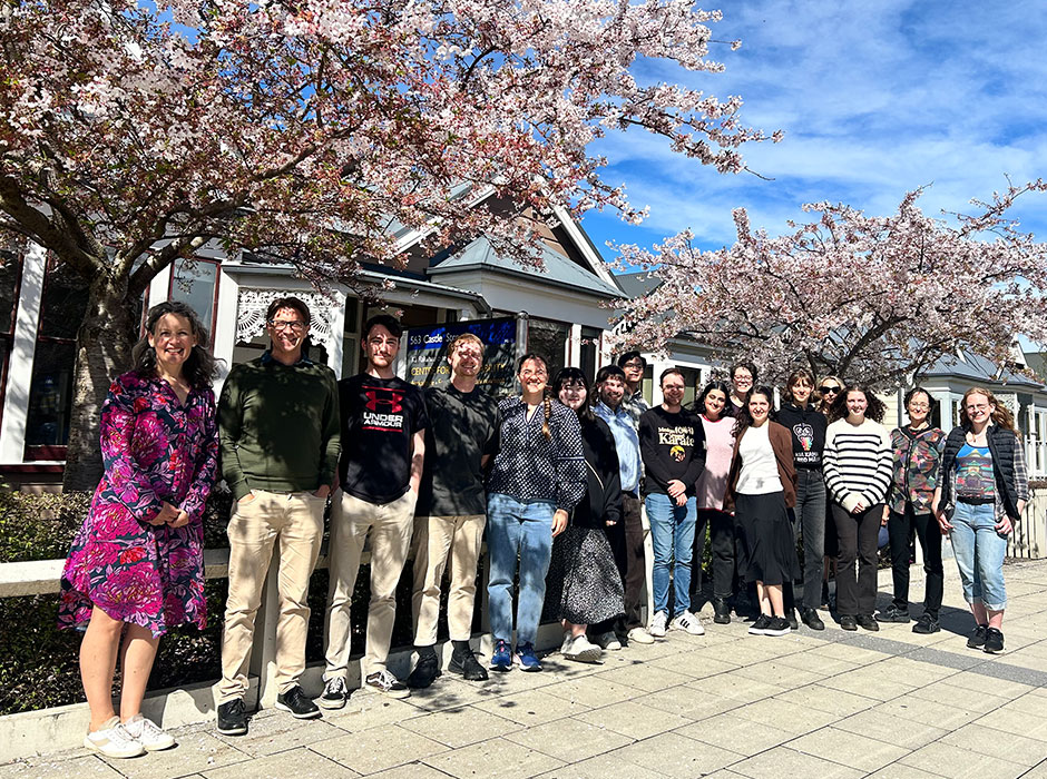 A large row of people standing in the sun under blossom trees