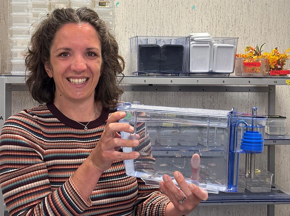 Dr Megan Leask pictured in a lab holding a container of small fish.
