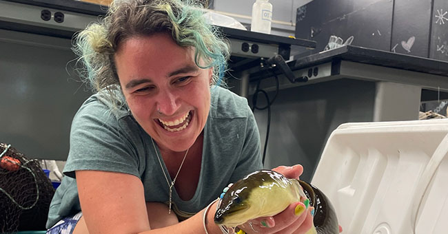 A smiling woman holding an eel 