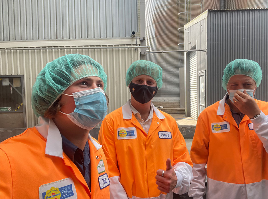 Three men in orange coveralls and wearing face masks and hair nets 