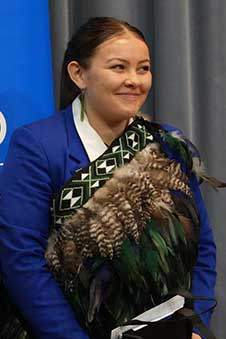 a young woman, cropped form her waist up, smiling