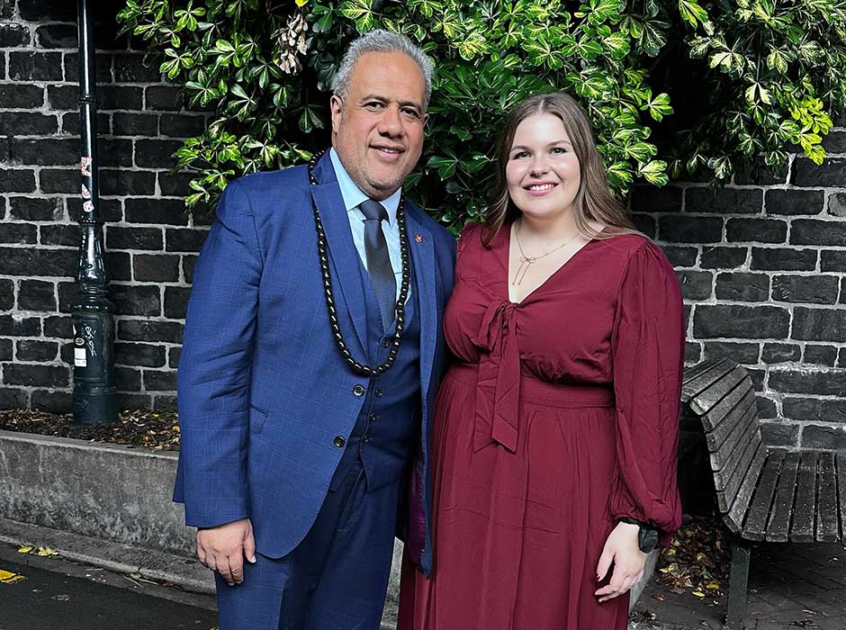 A man and a woman standing next to each other in front of a stone wall