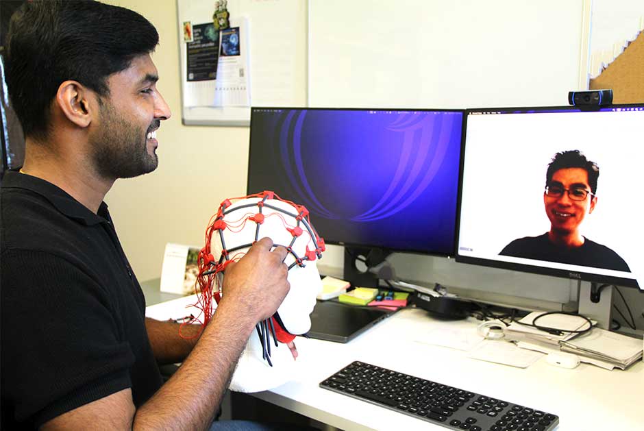 A person seated in front of computer with a person to speaking to them via the computer, face on screen