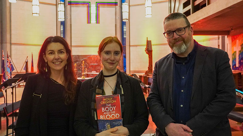 Three people pose for a photo in St Paul's Cathedral.