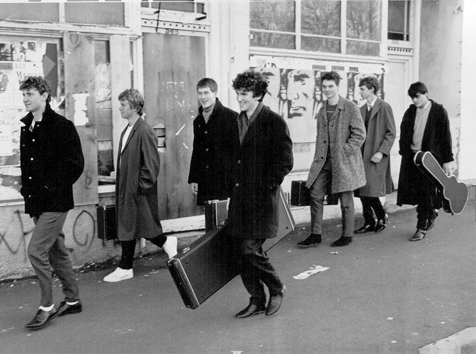 Band members walk along a street in a 1980s photo.