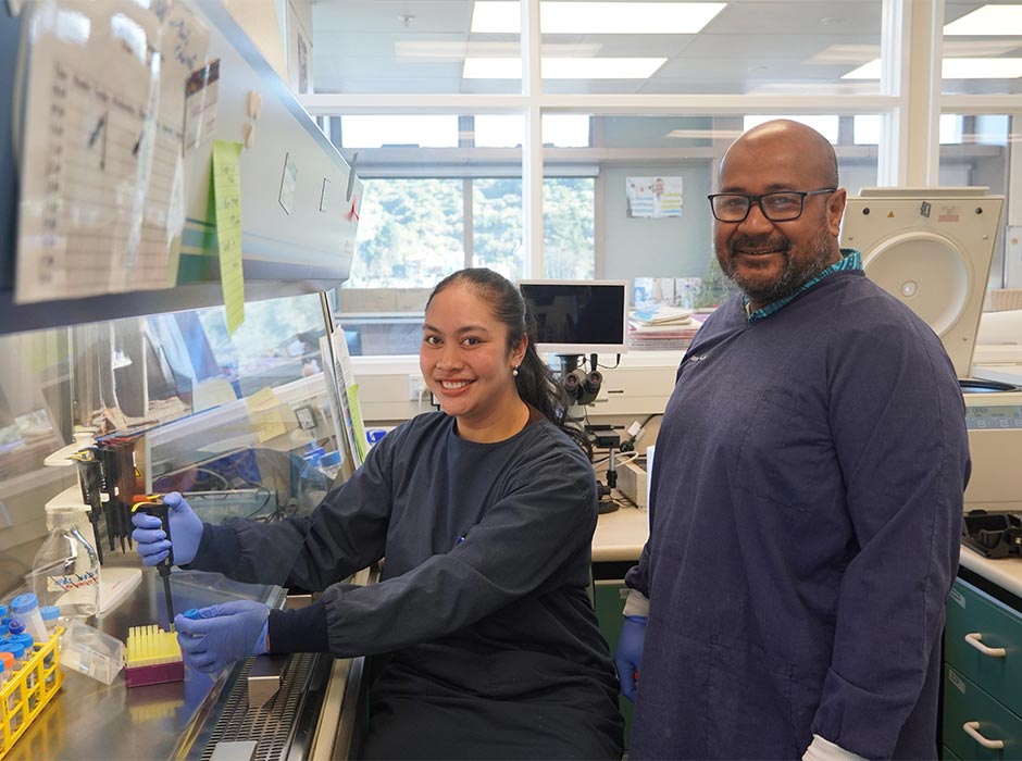 A seated woman and standing man are pictured in a lab.
