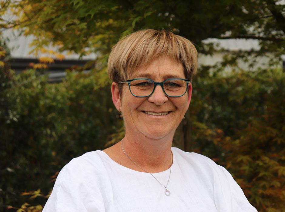A headshot of a woman wearing glasses pictured outside.