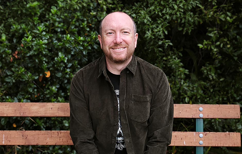 An author picture of Craig Cliff sitting on a park bench outside.