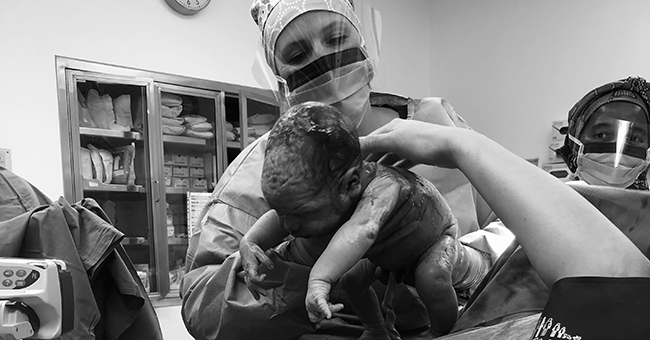 Mother and surgeon in hospital with new born baby delivered via caesarean section image.