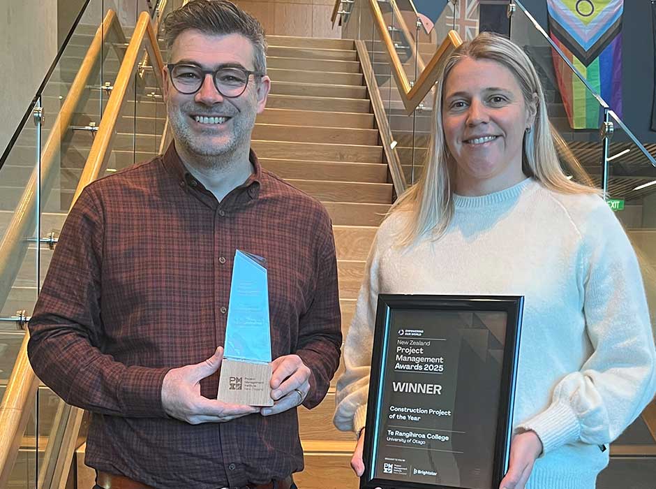 Two people standing on stairs each holding an award 