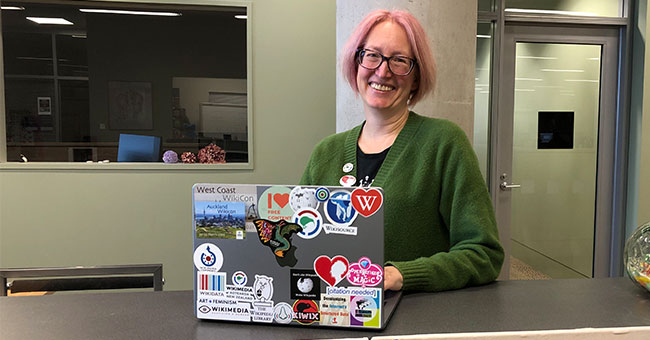 A woman standing holding a laptop 