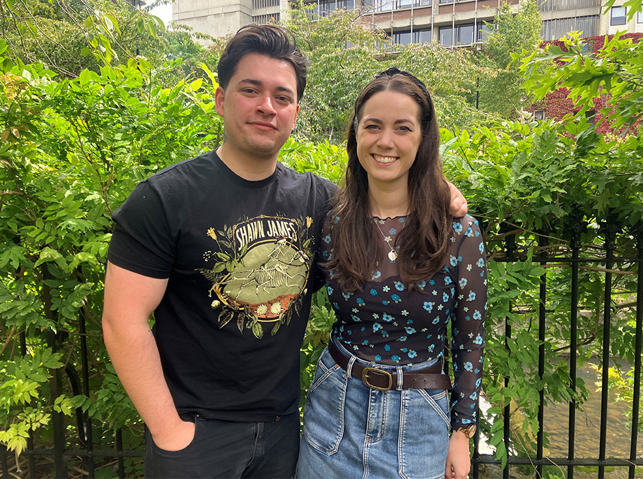 Two people leaning against a fence 