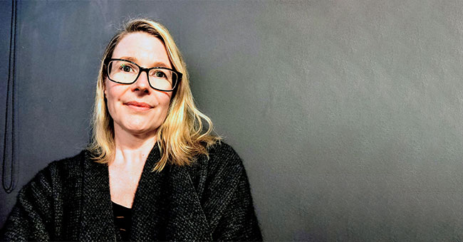 A woman seated against a black background