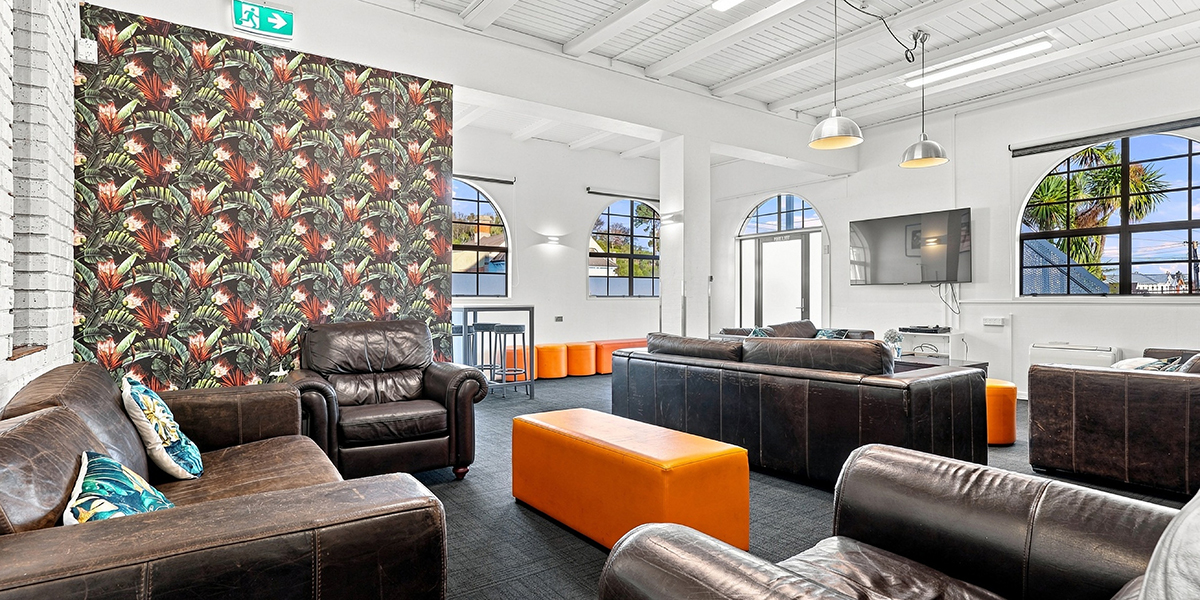 Shared lounge area with leather couches and TV