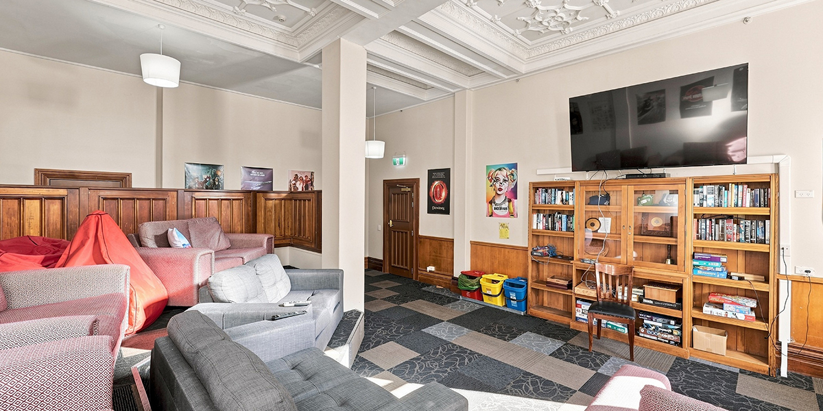 Room with couches and a large TV above bookshelves
