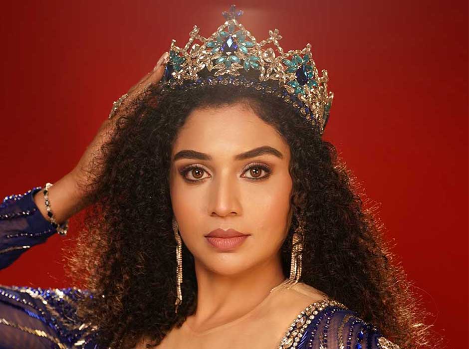 A close-up of a woman wearing a silver tiara with light and dark blue and clear stones on it