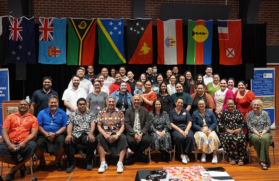Pacific staff group photo with Pacific flags on the wall in the background