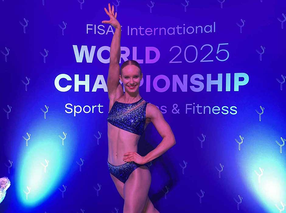 A woman poses in front of a sign saying FISA World 2025 championship