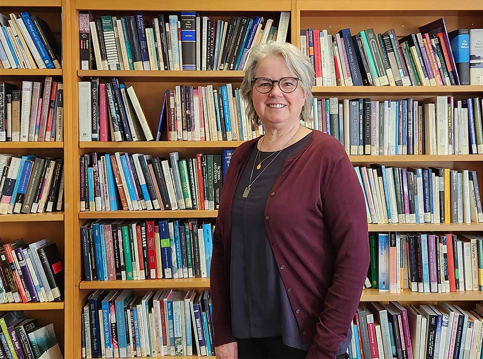 A woman standing in front of a book case 