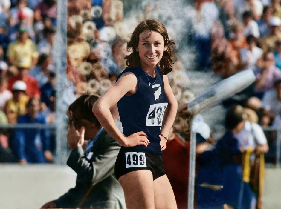 An older photo of a young female athlete, wearing a New Zealand sports kit, standing in front of a crowd.