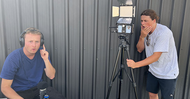Two men, one using audio equipment and the other using a camera