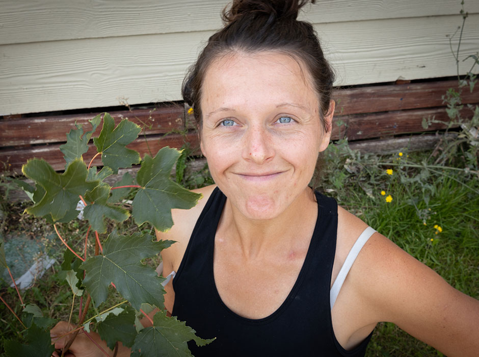 A woman looking up at the camera holding some sycamore leaves 