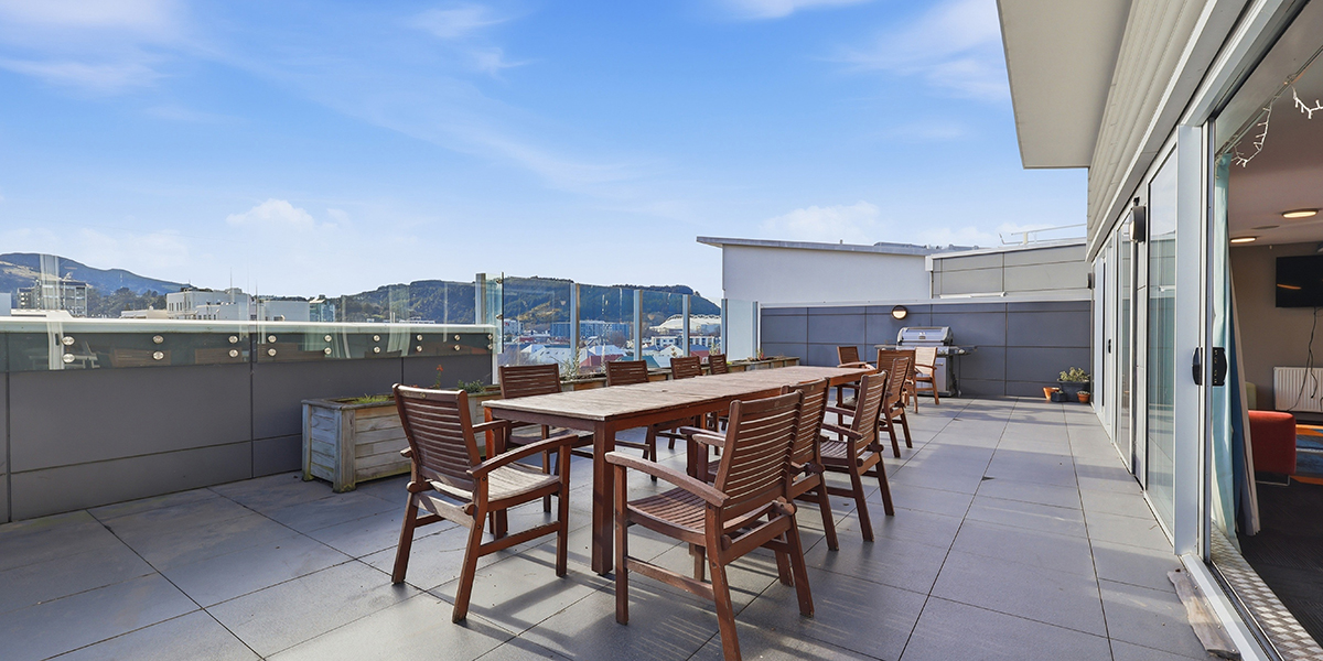 Table and chairs on outdoor deck area with view of city