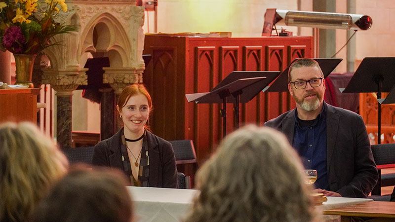 Two people listen to a talk at a book launch.