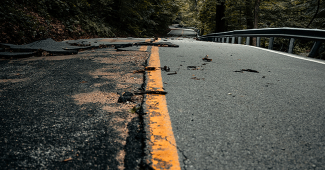 a broken road with yellow line down the middle
