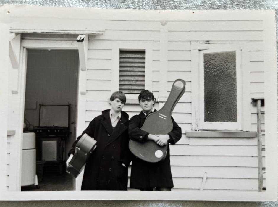 A black and white photo of two students outside a flat in the 1980s.