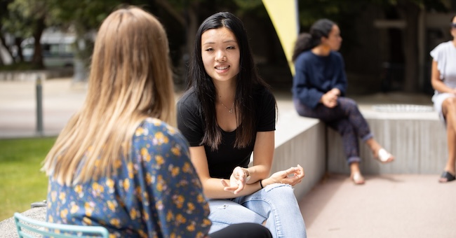 Students sitting in outdoor courtyard talking with each other image