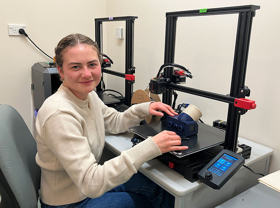 a woman sitting at a desk in front of machinery 