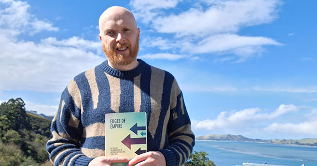 A man standing holding his book 