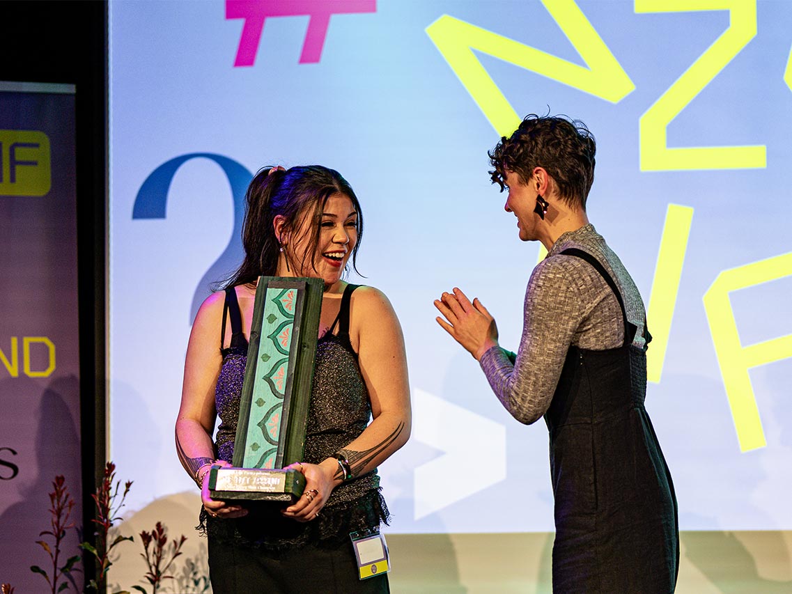 A woman receiving a trophy from another woman