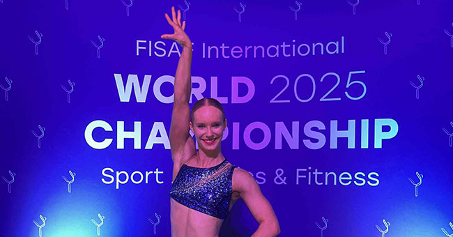 A woman poses in front of a sign saying FISA World 2025 championship
