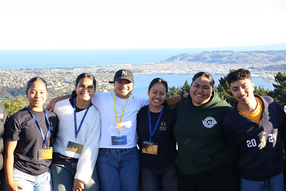 A small group of Pacific Island students in front of a view of Dunedin