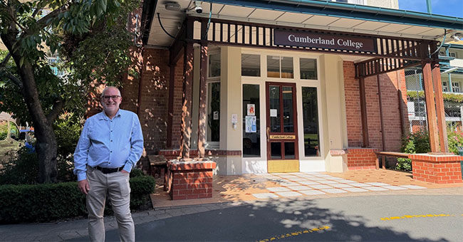 A man stands in front of Cumberland College.