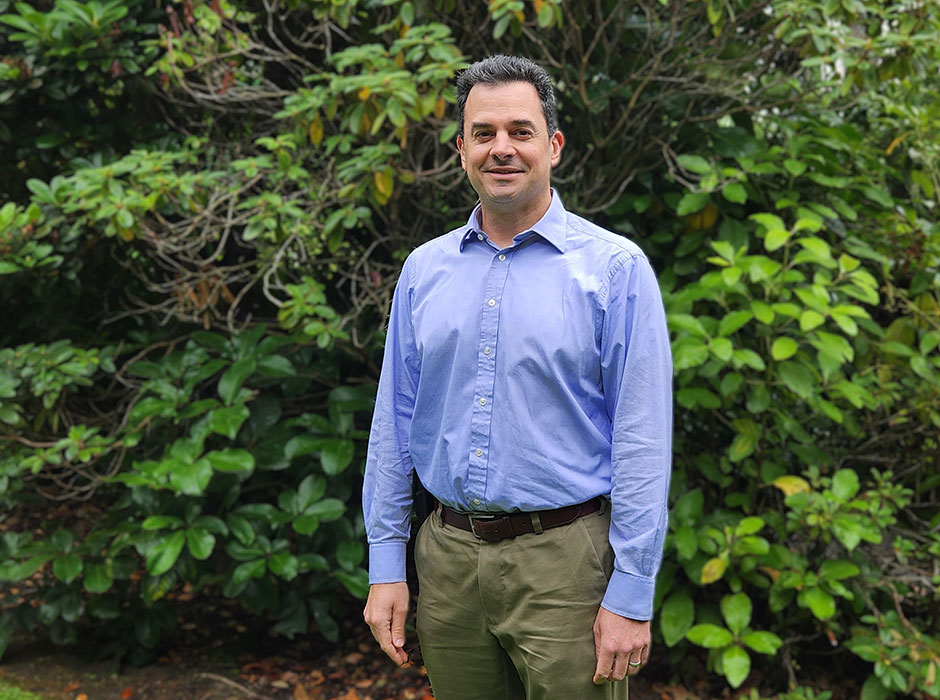 A man standing in front of greenery 