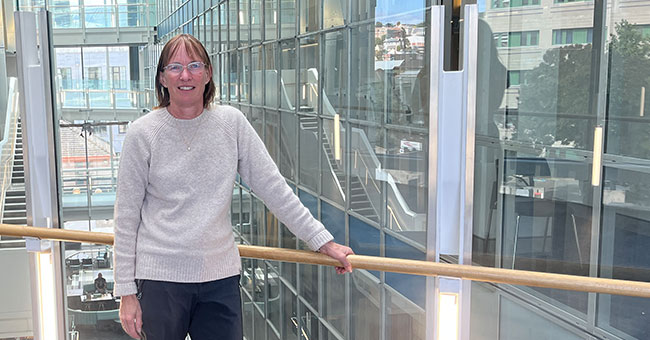 A woman standing in a building that has a lot of glass 